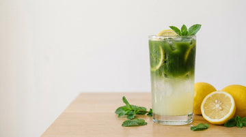 Tall glass of green iced NeuroMatcha lemonade with lemon and mint
